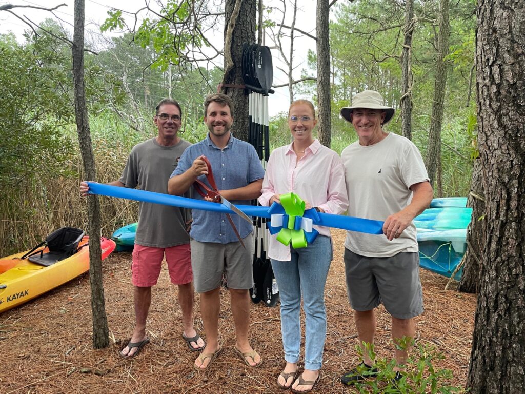 a group of people standing next to each other holding a blue ribbon