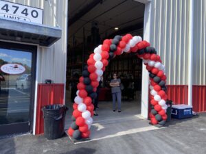 a red, white and black balloon arch in front of a building