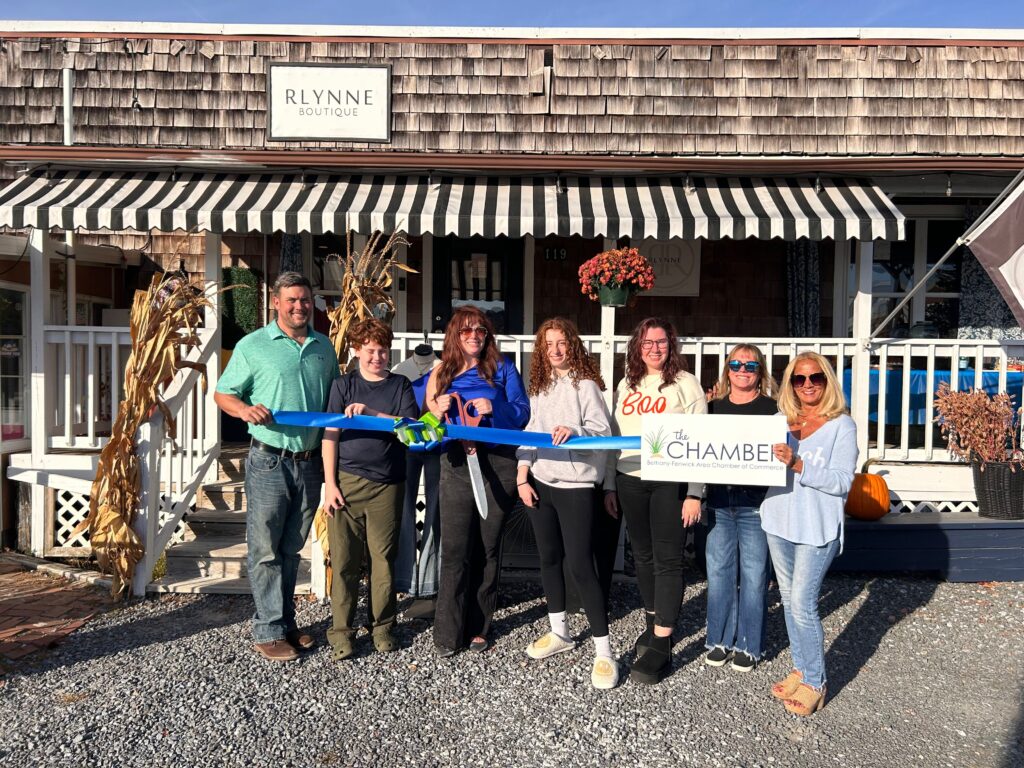 a group of people holding a ribbon in front of a store