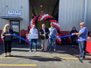 a group of people holding a ribbon in front of a building