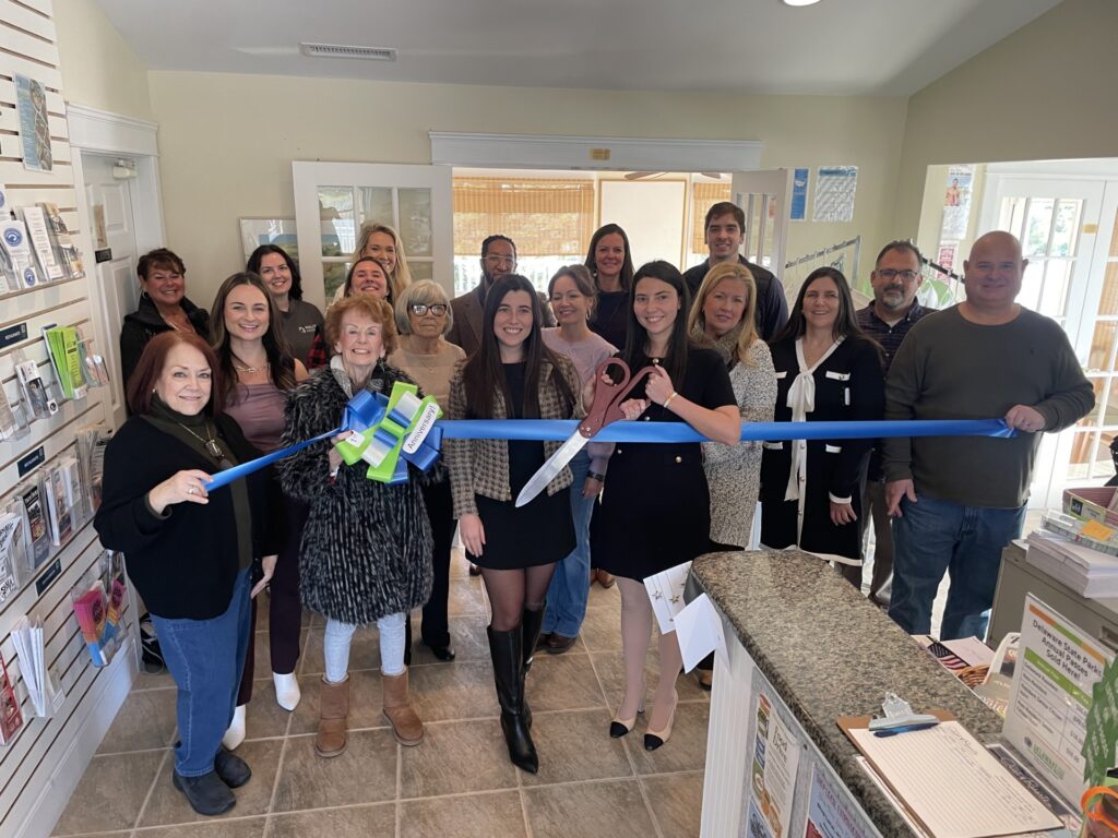 a group of people standing in a room holding a blue ribbon